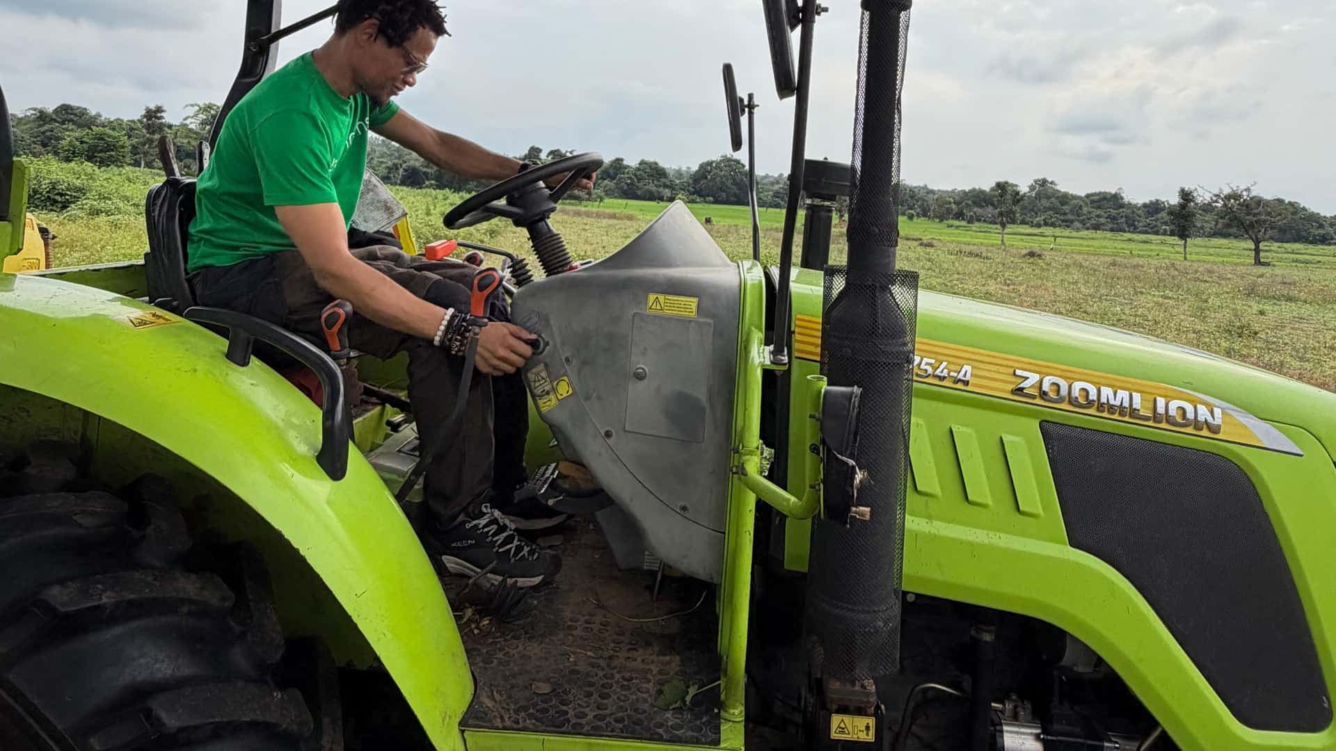 Ubuntu Farms operator at the controls of a tractor over open soybean fields in Nasarawa