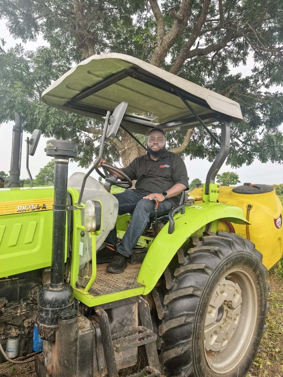 Team member seated on a tractor in the field