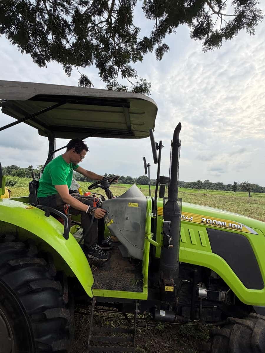 Operator on a tractor under a dramatic sky over open fields